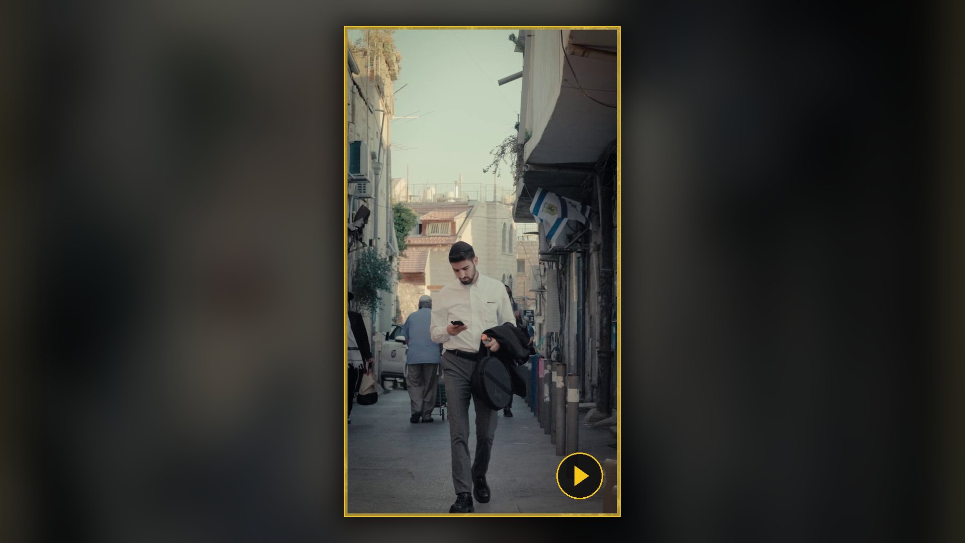 צעיר חרדי צועד בסמטה ומביט בטלפון